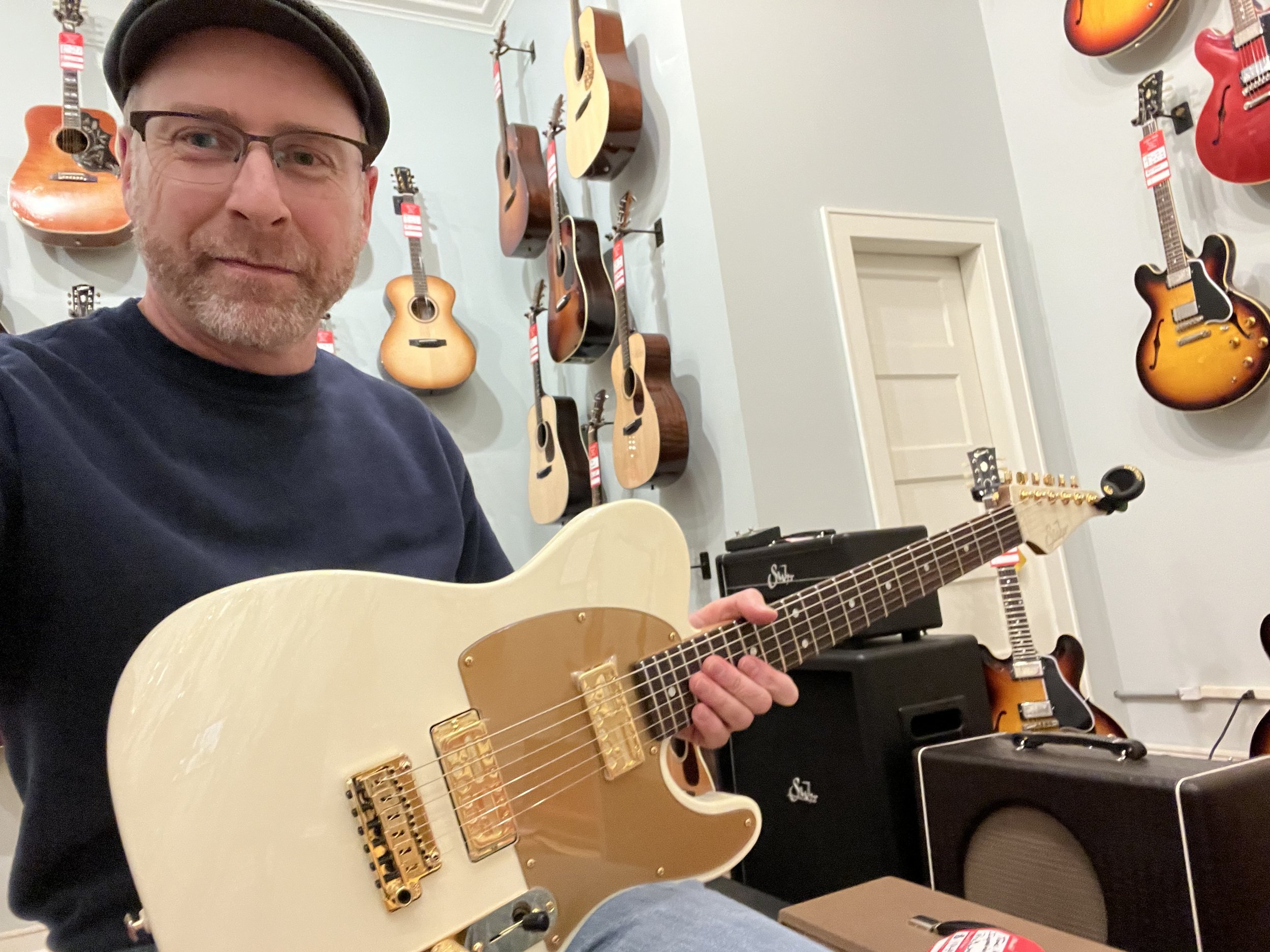 Erik at a guitar shop with a cream and gold Telecaster