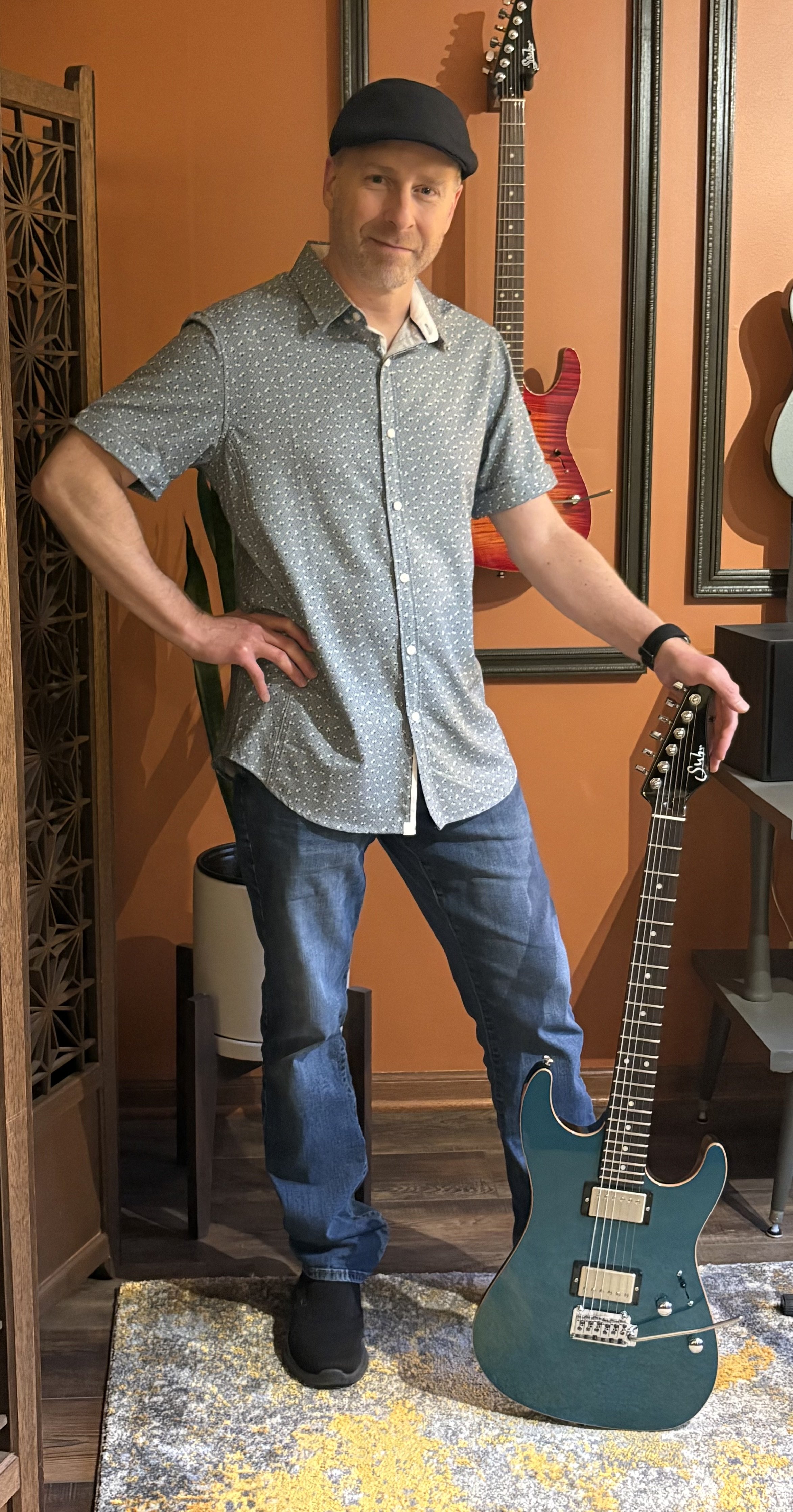 Erik Davis with a teal guitar against the studio's orange wall